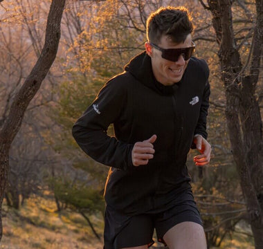 Male runner trail running through woods at sunset wearing affordable performance sports sunglasses