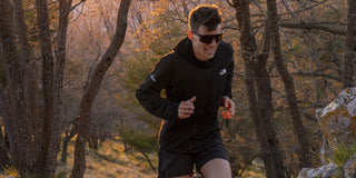 Male runner trail running through woods at sunset wearing affordable performance sports sunglasses